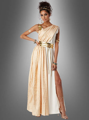 Eine Frau im „Griechische Göttin Hera“-Kostüm – ein gold-weißes Kleid im griechischen Stil mit hohem Schlitz, goldenen Accessoires und Riemchen-High-Heels – steht vor einem grauen Hintergrund mit Farbverlauf und ist damit das perfekte Toga-Party-Kleid oder griechische Göttinnen-Kostüm für Damen, die einen eleganten Göttinnen-Look suchen.