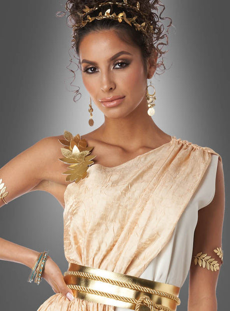 Eine Frau, geschmückt mit einer Krone aus Blattgold und Schmuck, präsentiert das „Griechische Göttin Hera“-Kostüm – ein cremefarbenes und goldfarbenes Kleid im Toga-Stil –, das sich ideal für Themenveranstaltungen oder als auffälliges Toga-Party-Kleid eignet, während sie elegant vor einem grauen Hintergrund mit Farbverlauf posiert.