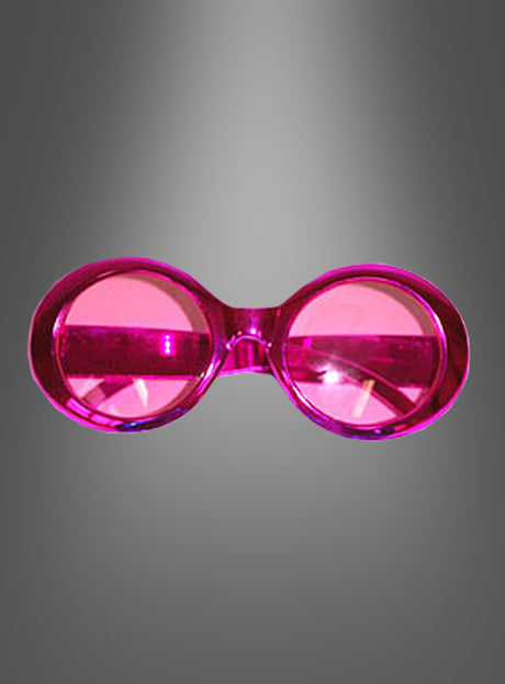 Hippie-Brille im Metallic-Look: Eine pinkfarbene, runde ausgefallene Brille mit Kunststoffrahmen und getönten Gläsern fängt den verspielten Charakter einer Retro-Brille aus den 70er Jahren ein und wird vor einem grau verlaufenden Hintergrund präsentiert.