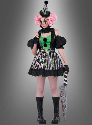 Eine Person, die das Damenkostüm „Verrückte Clownfrau Nicky“ trägt – bestehend aus einem bunten Clown-Outfit und einer rosa Perücke –, hält ein großes, blutiges Requisitenmesser in der Hand, während sie vor einem grauen Hintergrund steht.