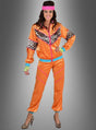 Eine Frau in einem XXL-Trainingsanzug im 80er-Jahre-Look in leuchtendem Orange mit Leopardenmuster-Details, kombiniert mit einem rosa Stirnband und passenden High Heels mit Leopardenmuster, steht lächelnd vor einem grauen Hintergrund – eine ideale Wahl für eine authentische 80er-Jahre-Party oder als auffälliges 80er-Jahre-Outfit.