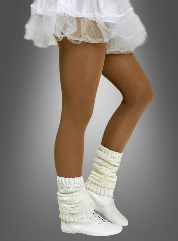 Eine Person, die die Tanzstrumpfhose für Kinder und Erwachsene in der Farbe „Tan“ trägt, kombiniert mit einem weißen Tutu, cremefarbenen Stulpen und weißen Tanzschuhen, steht auf Zehenspitzen vor einem grauen Hintergrund. Die blickdichte Tanzstrumpfhose für Kinder und Erwachsene verleiht dem Ensemble sowohl Eleganz als auch Tragekomfort.