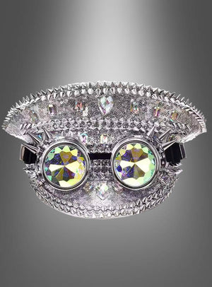 Eine Paillettenmütze im Festival-Stil in dekorativem Silber, verziert mit Stacheln und Strasssteinen, ist mit einer aufgesetzten runden, bunten Kaleidoskopbrille versehen und vor einem grauen Hintergrund abgebildet.