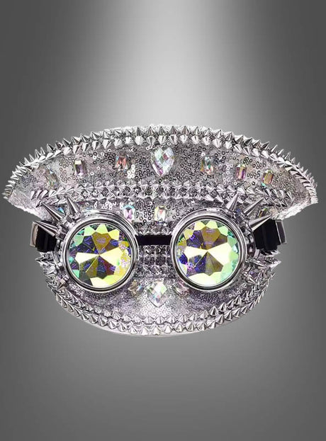 Eine Paillettenmütze im Festival-Stil in dekorativem Silber, verziert mit Stacheln und Strasssteinen, ist mit einer aufgesetzten runden, bunten Kaleidoskopbrille versehen und vor einem grauen Hintergrund abgebildet.