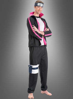 Ein Mann trägt das „Boruto“-Kostüm für Erwachsene aus „Naruto“ im Anime-Stil in Schwarz und Rosa, komplett mit Stirnband und Beutel, und steht barfuß mit verschränkten Armen vor einem grauen Hintergrund mit Farbverlauf.