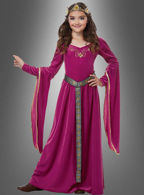 Ein Mädchen, das das Mittelalterkleid „Rose Prinzessin“ trägt – ein magentafarbenes Mittelalterkleid für Mädchen mit langen, ausgestelltem Ärmeln, goldenen Verzierungen, einem gemusterten Gürtel und einer goldenen Krone –, steht vor einem grauen Hintergrund.