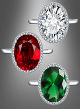 Drei „Ring mit großem Edelstein“-Modelle, jeweils mit einem ovalen Edelstein in Silber gefasst und von kleinen Diamanten umgeben: oben ein klarer Stein, in der Mitte ein roter Stein und unten ein grüner Stein.