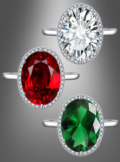 Drei „Ring mit großem Edelstein“-Modelle, jeweils mit einem ovalen Edelstein in Silber gefasst und von kleinen Diamanten umgeben: oben ein klarer Stein, in der Mitte ein roter Stein und unten ein grüner Stein.