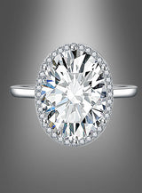Ring mit großem Edelstein: ein silberner Ring mit einem großen ovalen Mittelstein im Diamant-Look, umgeben von einem funkelnden Halo aus kleineren Steinen, präsentiert vor einem sanft verlaufenden grauen Hintergrund.