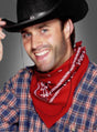 Ein lächelnder Mann in einem karierten Hemd, einem roten Cowboy-Bandana und einem schwarzen Cowboyhut zieht den Hut, während er vor einem schlichten grauen Hintergrund posiert.