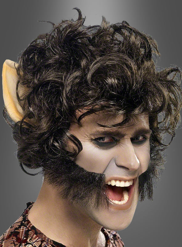 Eine Person mit wildem, lockigem Haar, gestylt mit einer Werwolf-Perücke mit Ohren, grauem Gesichts-Make-up, übertriebenen Koteletten, spitzen Ohrprothesen und entblößten Zähnen, die vor einem schlichten grauen Hintergrund posiert – perfekt für ein auffälliges Halloween-Kostüm.
