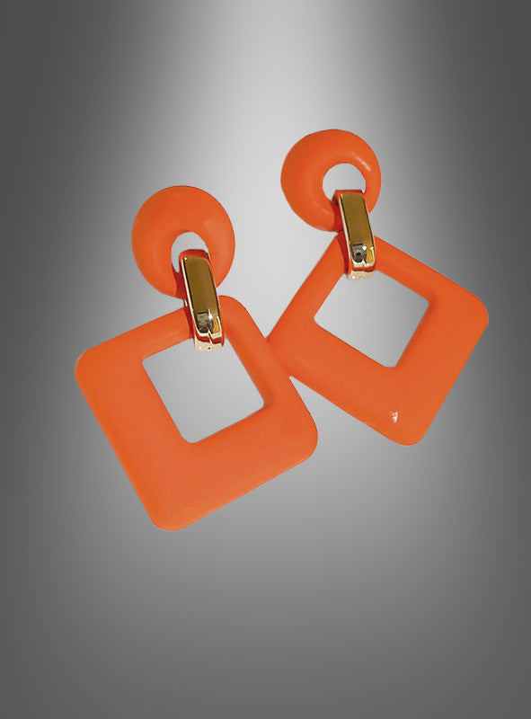 Ein Paar Retro-Ohrstecker aus den 60er Jahren – orangefarbene, geometrisch geformte Ohrringe mit goldenen Verbindungsstücken, bestehend aus runden Ohrsteckern und hohlen, quadratischen Anhängern – wird vor einem grau verlaufenden Hintergrund präsentiert.