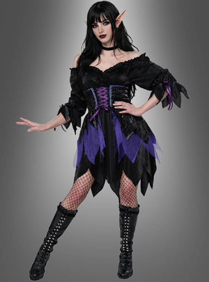 Eine Frau posiert im „Düstere Gothic Elfe“-Damenkostüm, das spitze Elfenohren, schwarze und violette Fantasy-Elemente, Netzstrumpfhosen, schwarze Stiefel und dunkles Make-up umfasst, vor einem grauen Hintergrund mit Farbverlauf.