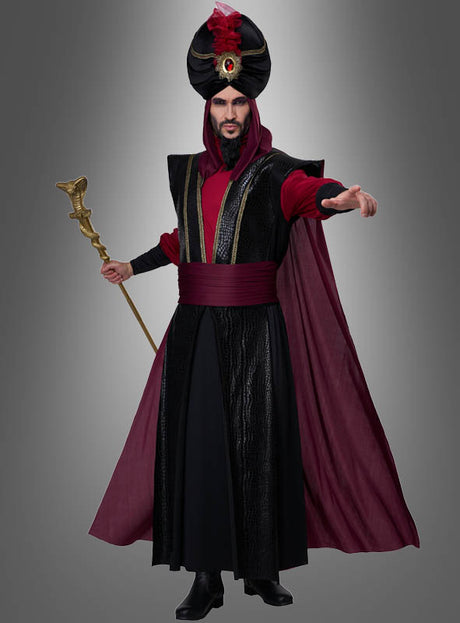 Eine Person, die das „Düsterer Sultan“-Kostüm für Herren trägt – ein schwarz-burgunderrotes, vom Orient inspiriertes Zaubererkostüm, komplett mit Turban, Umhang und Stab –, steht vor einem grauen Hintergrund und streckt eine Hand nach vorne; perfekt für jede „1001 Nacht“-Kostümparty oder jede Karnevalsfeier im Sultan-Stil.