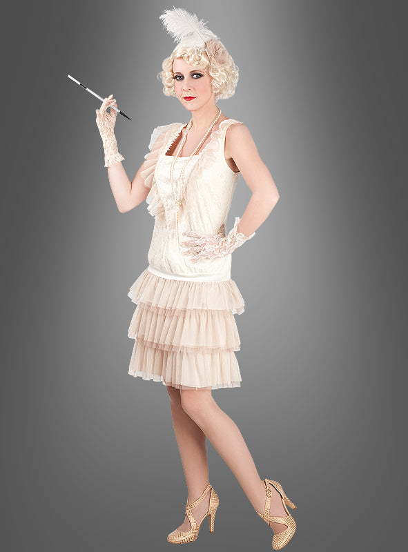Eine Person, die das „Charleston Lady“-Damenkostüm trägt – bestehend aus einem glamourösen Flapper-Kleid im Stil der 1920er Jahre, Handschuhen, Stöckelschuhen, einem Kopfschmuck mit Federn und einer Zigarettenspitze –, steht vor einem schlichten grauen Hintergrund.