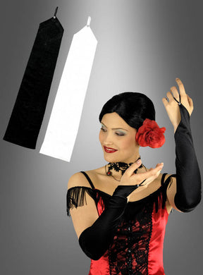 Eine Frau in einem rot-schwarzen Kleid posiert mit schwarzen Opernhandschuhen, die mit eleganten Strasssteinen verziert sind; über ihr sind vor einem grauen Hintergrund ein Paar Handschuhe mit Fingerschlaufe und Strass – einer in Schwarz, einer in Weiß – zu sehen.
