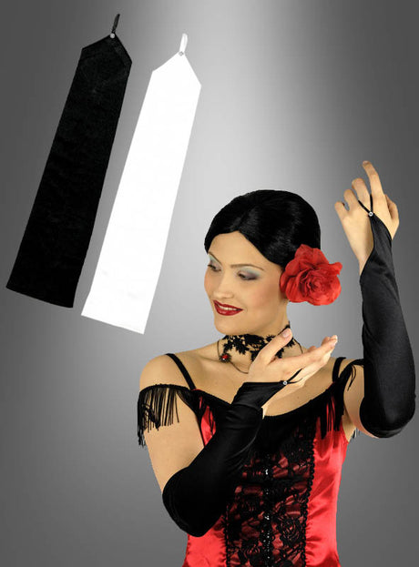 Eine Frau in einem rot-schwarzen Kleid posiert mit schwarzen Opernhandschuhen, die mit eleganten Strasssteinen verziert sind; über ihr sind vor einem grauen Hintergrund ein Paar Handschuhe mit Fingerschlaufe und Strass – einer in Schwarz, einer in Weiß – zu sehen.