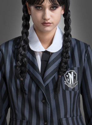 Eine Person trägt die „Wednesday“-Damen-Schuluniform in Schwarz und Grau, bestehend aus einem schwarz-grau gestreiften Blazer mit Wappenabzeichen, kombiniert mit einem weißen Hemd mit Kragen, einer schwarzen Krawatte und zwei geflochtenen Zöpfen – damit wird der ikonische „Wednesday“-Look für Damen nachgebildet, der von der Schuluniform der Nevermore Academy aus dem „Addams Family“-Kostümstil inspiriert ist.