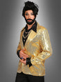 Eine Person, die eine glänzende goldene Paillettenjacke für Herren, ein schwarzes Hemd, mehrere Halsketten, einen künstlichen Bart und eine gestylte schwarze Perücke trägt, steht vor einem grauen Hintergrund mit Farbverlauf – ein auffälliges Karnevalsoutfit, das alle Blicke auf sich zieht.