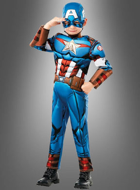 Ein Kind, das das „Captain America“-Kinder-Muskelkostüm Deluxe trägt, posiert mit einer Hand an der Stirn vor einem grauen Hintergrund mit Farbverlauf. Dieses Deluxe-Kinderkostüm ist perfekt für kleine Helden, die sich als ihre Lieblingsfigur aus der Welt der Superhelden verkleiden möchten.