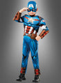 Ein Kind, das das „Captain America“-Kinder-Muskelkostüm Deluxe trägt, posiert mit einer Hand an der Stirn vor einem grauen Hintergrund mit Farbverlauf. Dieses Deluxe-Kinderkostüm ist perfekt für kleine Helden, die sich als ihre Lieblingsfigur aus der Welt der Superhelden verkleiden möchten.