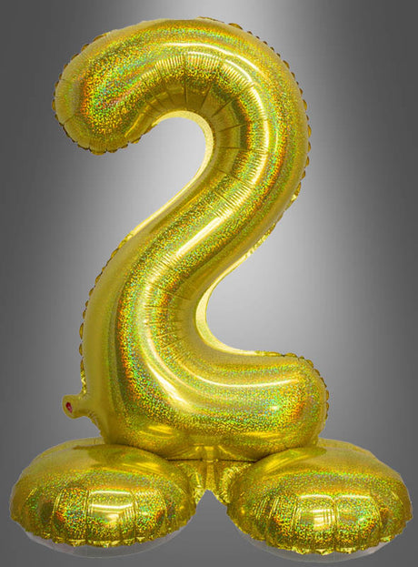 Der AirLoon-Folienballon „Zahlen zum Kombinieren“ (70 cm, stehend) in Form einer glänzenden goldenen Zwei steht aufrecht auf zwei runden Ballonständern und ist damit das perfekte Deko-Accessoire für einen Geburtstag vor einem grauen Farbverlaufshintergrund.