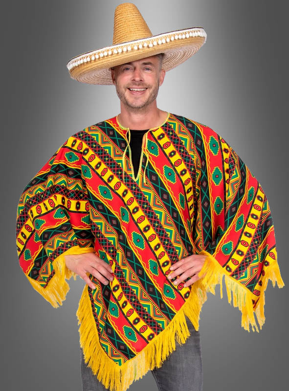 Ein Mann, der einen großen Strohsombrero und den farbenfrohen „Mexikaner“-Poncho „Juan“ mit gelben Fransen trägt, steht lächelnd vor einem grauen Hintergrund mit Farbverlauf – perfekt für jede „Fiesta Mexicana“ oder als klassisches mexikanisches Kostüm.