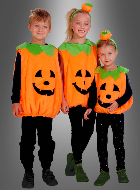 Drei Kinder, die alle das gleiche Deluxe-Kürbiskostüm aus Plüsch für Kinder mit grünen Kragen tragen, stehen zusammen vor einem grau abgestuften Hintergrund und lächeln – ein bezaubernder Halloween-Look für Kinder.