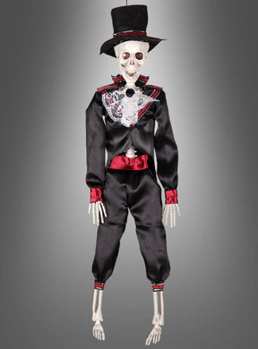 Die 42 cm große „Tag der Toten“-Voodoo-Puppe – erhältlich als Braut oder Bräutigam – zeigt eine Skelettfigur in einem schwarzen Anzug mit roten Akzenten und einem Zylinder, die vor einem grauen Hintergrund mit Farbverlauf posiert. Diese auffällige Dekoration eignet sich perfekt, um mexikanisches Halloween zu feiern oder die Tradition des Skelett-Brautpaares zu würdigen.