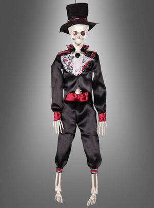 Die 42 cm große „Tag der Toten“-Voodoo-Puppe – erhältlich als Braut oder Bräutigam – zeigt eine Skelettfigur in einem schwarzen Anzug mit roten Akzenten und einem Zylinder, die vor einem grauen Hintergrund mit Farbverlauf posiert. Diese auffällige Dekoration eignet sich perfekt, um mexikanisches Halloween zu feiern oder die Tradition des Skelett-Brautpaares zu würdigen.