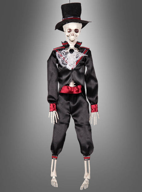 Die 42 cm große „Tag der Toten“-Voodoo-Puppe – erhältlich als Braut oder Bräutigam – zeigt eine Skelettfigur in einem schwarzen Anzug mit roten Akzenten und einem Zylinder, die vor einem grauen Hintergrund mit Farbverlauf posiert. Diese auffällige Dekoration eignet sich perfekt, um mexikanisches Halloween zu feiern oder die Tradition des Skelett-Brautpaares zu würdigen.