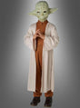 Ein Kind im Yoda-Kinderkostüm „Original STAR WARS“ – mit einer Yoda-Maske, einem braunen Outfit und einer langen beigen Robe – steht mit gefalteten Händen vor einem grauen Hintergrund und ist damit ideal für Fans, die ein authentisches STAR WARS-Kostüm suchen.