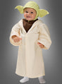 Ein kleines Kind, das das originale STAR WARS-Kinderkostüm von Yoda trägt – bestehend aus einem grünen Hut und einer cremefarbenen Robe –, steht vor einem grauen Hintergrund.