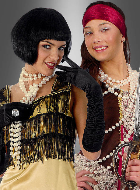 Zwei Frauen in Kostümen: Die eine trägt ein gelbes Flapper-Kleid mit schwarzen Handschuhen und einer „Deluxe Perlenkette Modeschmuck creme“, die andere ist als Piratin verkleidet, mit einem roten Stirnband, mehreren Perlenketten – darunter auch die „Deluxe Perlenkette Modeschmuck creme“ – und hält ein Schwert in der Hand; beide stehen nebeneinander.