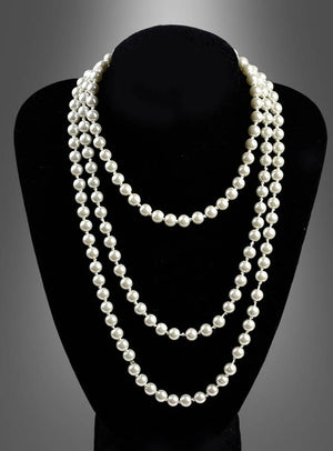 Auf einem schwarzen Ausstellungsständer wird die „Deluxe Perlenkette Modeschmuck creme“ präsentiert, eine dreisträngige Halskette mit runden, weißen Perlen, die vor einem grauen Hintergrund mit Farbverlauf zur Geltung kommt.
