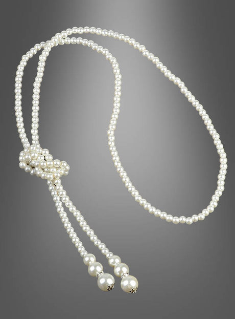 Die „Deluxe Perlenkette Modeschmuck creme“ ist eine lange, einsträngige Kette aus weißen Perlen, die nahe einem Ende geknotet ist und zwei lose Enden aufweist, die jeweils mit größeren runden Perlen abgeschlossen sind; sie wird vor einem grauen Hintergrund mit Farbverlauf präsentiert.