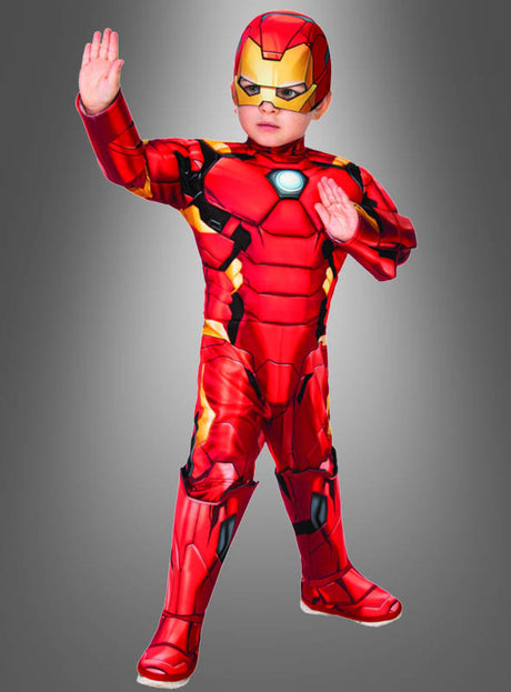 Ein Kind im „Deluxe Iron Man“-Kostüm für Kleinkinder, das sich durch kräftige rote und gelbe Farben auszeichnet, posiert heldenhaft mit einer erhobenen Hand und der anderen vor der Brust vor einem grauen Hintergrund mit Farbverlauf und verkörpert so den Geist dieses legendären Superhelden-Kostüms.