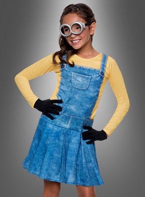 Ein Mädchen in einem Minion-Mädchenkostüm – bestehend aus einem gelben Langarmshirt, einem Overall mit Jeansprint, schwarzen Handschuhen und einer silbernen Schutzbrille – posiert vor einem grauen Hintergrund. Dieses verspielte Kostüm fängt den kultigen Look, den Minion-Fans so lieben, perfekt ein.