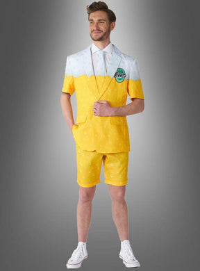 Ein Mann im „Sommerlicher Bieranzug“ – einem gelb-weißen Outfit mit Shorts, die einem Bierglas nachempfunden sind – steht vor einem grauen Hintergrund mit Farbverlauf und präsentiert damit das perfekte Sommeroutfit für jeden Bierliebhaber.