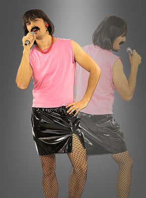 Eine Person, die ein rosa, ärmelloses Oberteil, einen schwarzen Rock, Netzstrümpfe und eine Perücke trägt und ein Mikrofon in der Hand hält, während sich hinter ihr ihr Spiegelbild abzeichnet – ideal für alle, die das „80er-Rockstar-Sänger-Hausfrau-Freddy“-Kostüm verkörpern möchten, das vom Musikvideo zu „I Want to Break Free“ von Queen inspiriert ist.