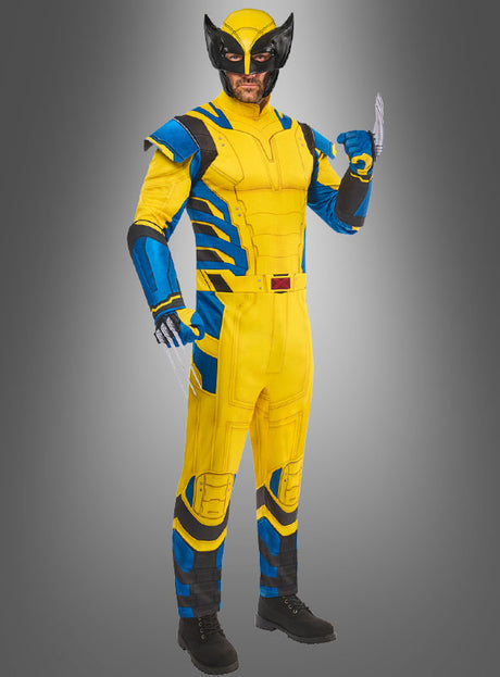 Eine Person, die das Wolverine-Kostüm für Herren trägt – in den Farben Gelb und Blau, mit einer schwarzen Maske, Metallklauen und schwarzen Stiefeln –, steht vor einem grauen Hintergrund mit Farbverlauf.