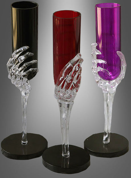 Drei elegante Sektgläser der Serie „Skeletthand“ in schmaler Form – eines in Schwarz, eines in Rot und eines in Lila –, die jeweils einen durchsichtigen Skelettarm als Stiel aufweisen, sind vor einem grauen Hintergrund ausgestellt. Diese einzigartigen Halloween-Sektgläser eignen sich perfekt als auffällige Halloween-Partydekoration für Ihre gruselige Feier.