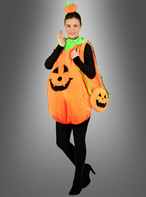 Eine Person, die das Kürbis-Plüschkostüm für Erwachsene trägt – mit einem Jack-o'-Lantern-Gesicht, schwarzer Kleidung darunter, einem kleinen Kürbishut und einer kürbisförmigen Tasche in der Hand – steht vor einem grauen Hintergrund. Dieses Kostüm eignet sich perfekt als Halloween-Kostüm für Erwachsene oder als Teil eines Gruppenkostüms für festliche Anlässe.