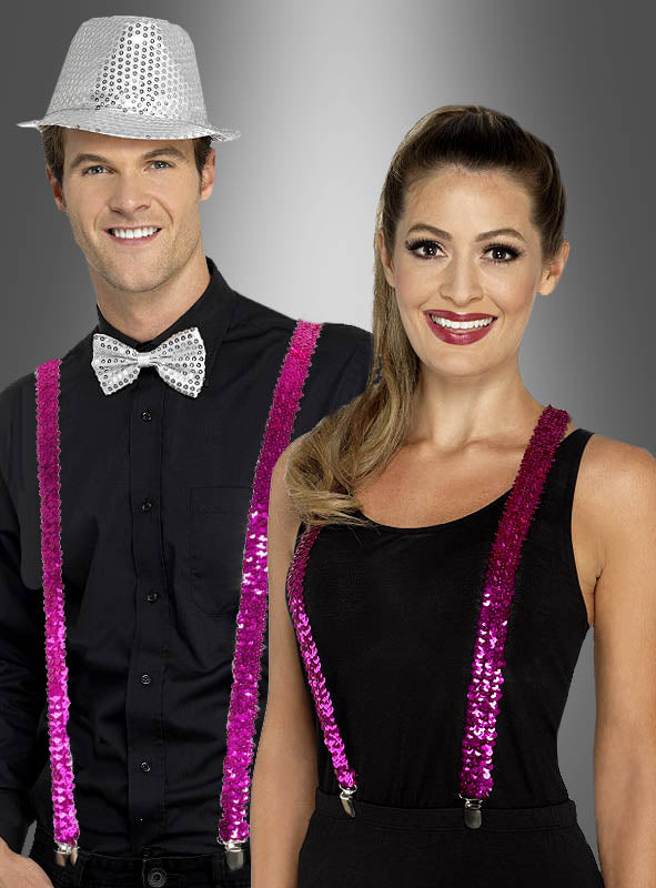 Ein Mann in Schwarz mit einem silbernen Paillettenhut und einer Fliege steht neben einer Frau in Schwarz; beide tragen die „Pailletten Hosenträger“ in Rosa – perfekte Fasching-Accessoires – vor einem grauen Hintergrund mit Farbverlauf.