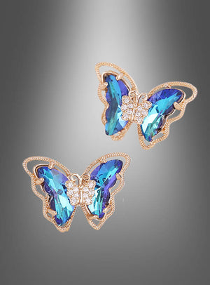 Schmetterling-Ohrstecker, schillernd, mit blauen Edelsteinflügeln und kleinen klaren Steinen am Körper, dargestellt vor einem grauen Hintergrund mit Farbverlauf.