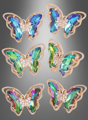 Sechs mit Edelsteinen besetzte Schmetterlingsbroschen mit goldenen Konturen und schillernden blauen, grünen und violetten Flügeln sind in zwei Reihen auf einem grauen Hintergrund mit Farbverlauf angeordnet – perfekt als Accessoire zu einem Schmetterling-Kostüm oder in Kombination mit den eleganten, schillernden Schmetterling-Ohrsteckern.