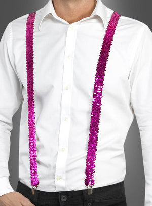 Eine Person, die ein weißes Hemd, eine schwarze Hose und die „Pailletten Hosenträger“ in Rosa vor grauem Hintergrund trägt und damit stilvolle Fasching-Accessoires präsentiert.