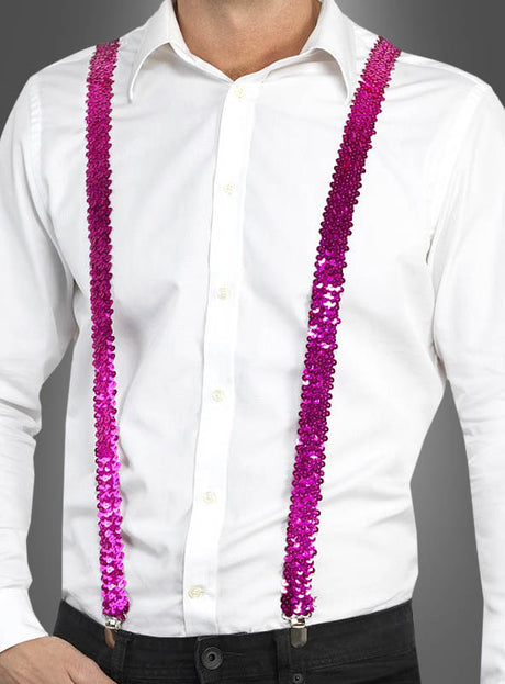 Eine Person, die ein weißes Hemd, eine schwarze Hose und die „Pailletten Hosenträger“ in Rosa vor grauem Hintergrund trägt und damit stilvolle Fasching-Accessoires präsentiert.
