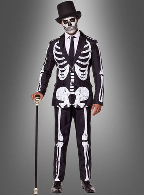 Eine Person, die den „Skelett Anzug Halloween Suitmeister“ trägt, mit passender Gesichtsbemalung und einem schwarzen Zylinder, die einen Spazierstock in der Hand hält und vor einem grauen Hintergrund mit Farbverlauf steht.
