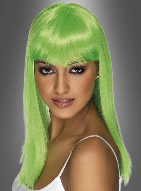 Eine Frau mit langen, glatten, leuchtend grünen Haaren und Pony, die ein weißes Oberteil trägt und vor einem grauen Hintergrund mit Farbverlauf posiert – eine auffällige „Glamour Leucht“-Perücke in Neonfarben, perfekt für eine 80er-Jahre-Party.